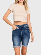 Load image into Gallery viewer, Woman wearing blue high rise bermuda denim shorts with rolled cuffs and a beige crop tee, casual summer style - 2
