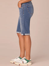 Load image into Gallery viewer, Women's medium blue artisanal denim Bermuda shorts with rolled cuffs and gold button, paired with white sneakers - 3