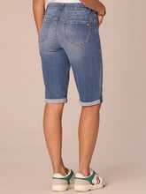 Load image into Gallery viewer, Women's medium blue artisanal denim Bermuda shorts with rolled cuffs and gold button, paired with white sneakers - 4