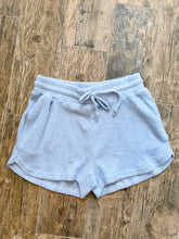 Load image into Gallery viewer, Light blue waffle knit thermal shorts with drawstring waistband and side pockets laid flat on wood surface - 1