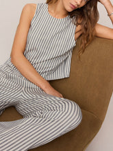 Load image into Gallery viewer, Woman wearing Sloane Knit Striped Top in Eclipse with matching striped pants, seated on olive chair - 1