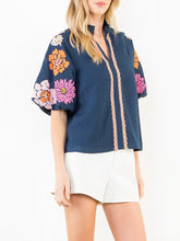 Load image into Gallery viewer, Navy textured top with bold floral embroidered sleeves and scalloped trim detail, paired with white shorts - 6

