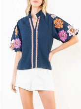 Load image into Gallery viewer, Navy textured top with bold floral embroidered sleeves and scalloped trim detail, paired with white shorts - 1

