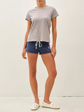 Load image into Gallery viewer, Woman wearing a light gray cotton slub crew neck tee with short sleeves, paired with navy athletic shorts. - 2
