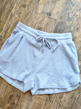 Load image into Gallery viewer, Light blue waffle knit thermal shorts with drawstring waistband and side pockets laid flat on wood surface - 2

