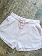 Load image into Gallery viewer, Light pink thermal waffle knit drawstring shorts with curved hem, laid flat on wood floor - 2
