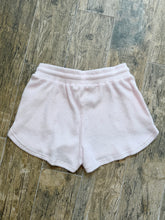 Load image into Gallery viewer, Light pink thermal waffle knit drawstring shorts with curved hem, laid flat on wood floor - 3
