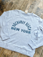 Load image into Gallery viewer, Light blue thermal crew sweatshirt with Rockaway Beach New York graphic print, laid flat on wood floor - 1
