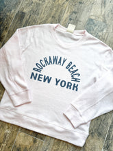 Load image into Gallery viewer, Pink thermal crew sweatshirt with Rockaway Beach New York graphic print in navy blue on wood floor background - 2
