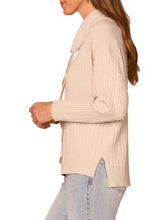Load image into Gallery viewer, Woman wearing a cream cable knit cowl neck sweater with drawstring detail and long sleeves paired with jeans - 3
