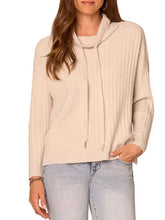 Load image into Gallery viewer, Woman wearing a cream cable knit cowl neck sweater with drawstring detail and long sleeves paired with jeans - 1

