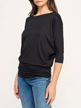 Load image into Gallery viewer, Black dolman boat neck top with 3/4 sleeves and relaxed fit, paired with blue jeans - 4
